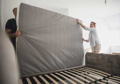 Man and woman throwing out bed bug infested mattress
