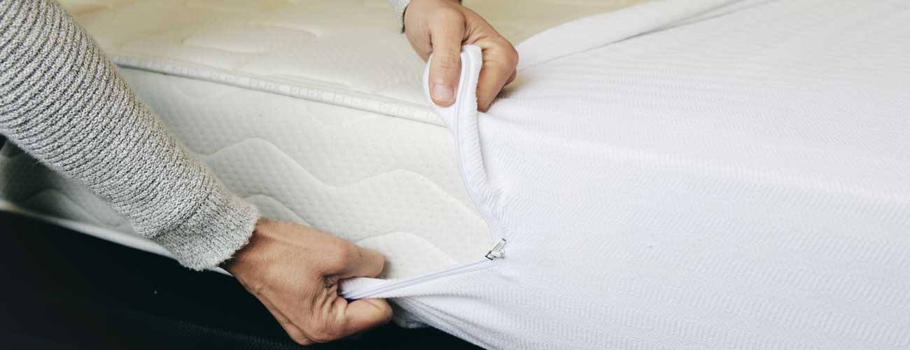 Man putting on bed cover to prevent bed bugs