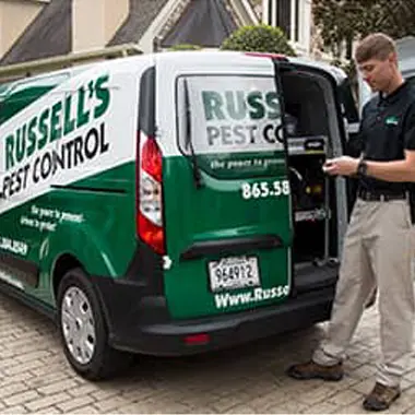 Exterminator standing at the rear of work van | Russell's Pest Control serving Knoxville, TN